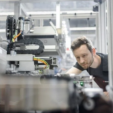 Worker inspecting polymer injection molding machinery